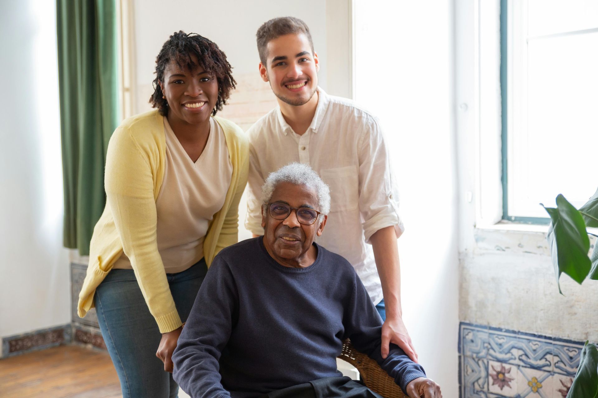 A group of people are posing for a picture with an elderly man in a wheelchair.