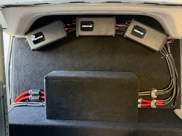 Car audio system with three amplifiers and a subwoofer installed in a vehicle.