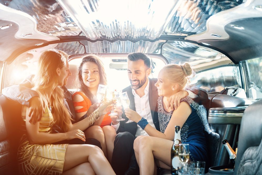 Group of friends smiling and drinking in a brightly lit limo interior