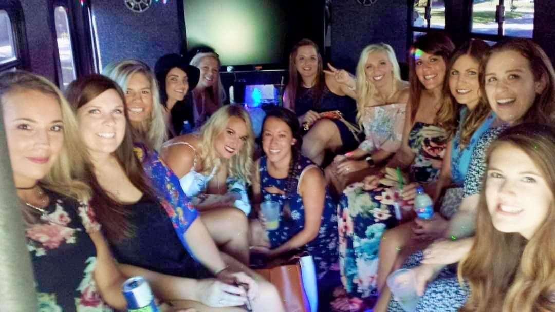 Group of friends posing together on a couch in a dimly lit room with colorful party lights