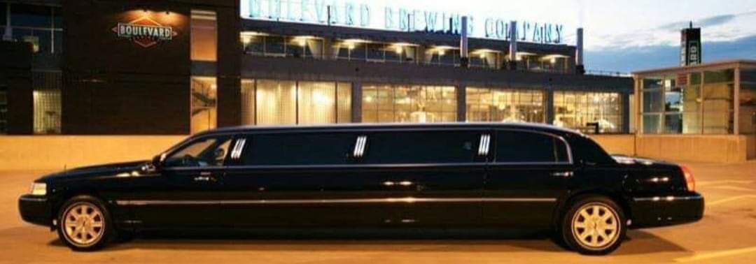 Black stretch limousine parked outside a lit building at night