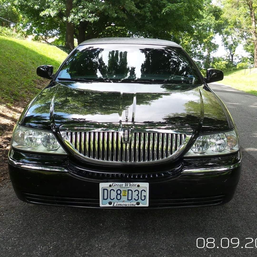 Front view of a black sedan parked on a tree-lined road