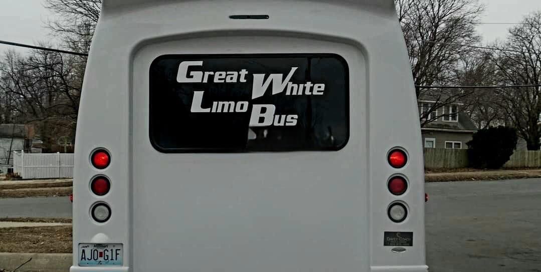Rear of a white bus with “Great White” on the back window and red lights on either side.