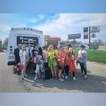 Group of people in bright safety vests posing beside a truck at a roadside stop