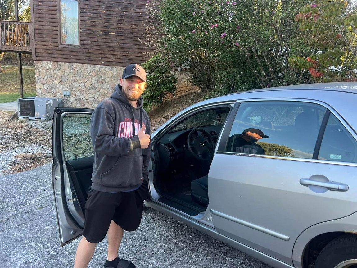 A man is standing next to a car with the door open.