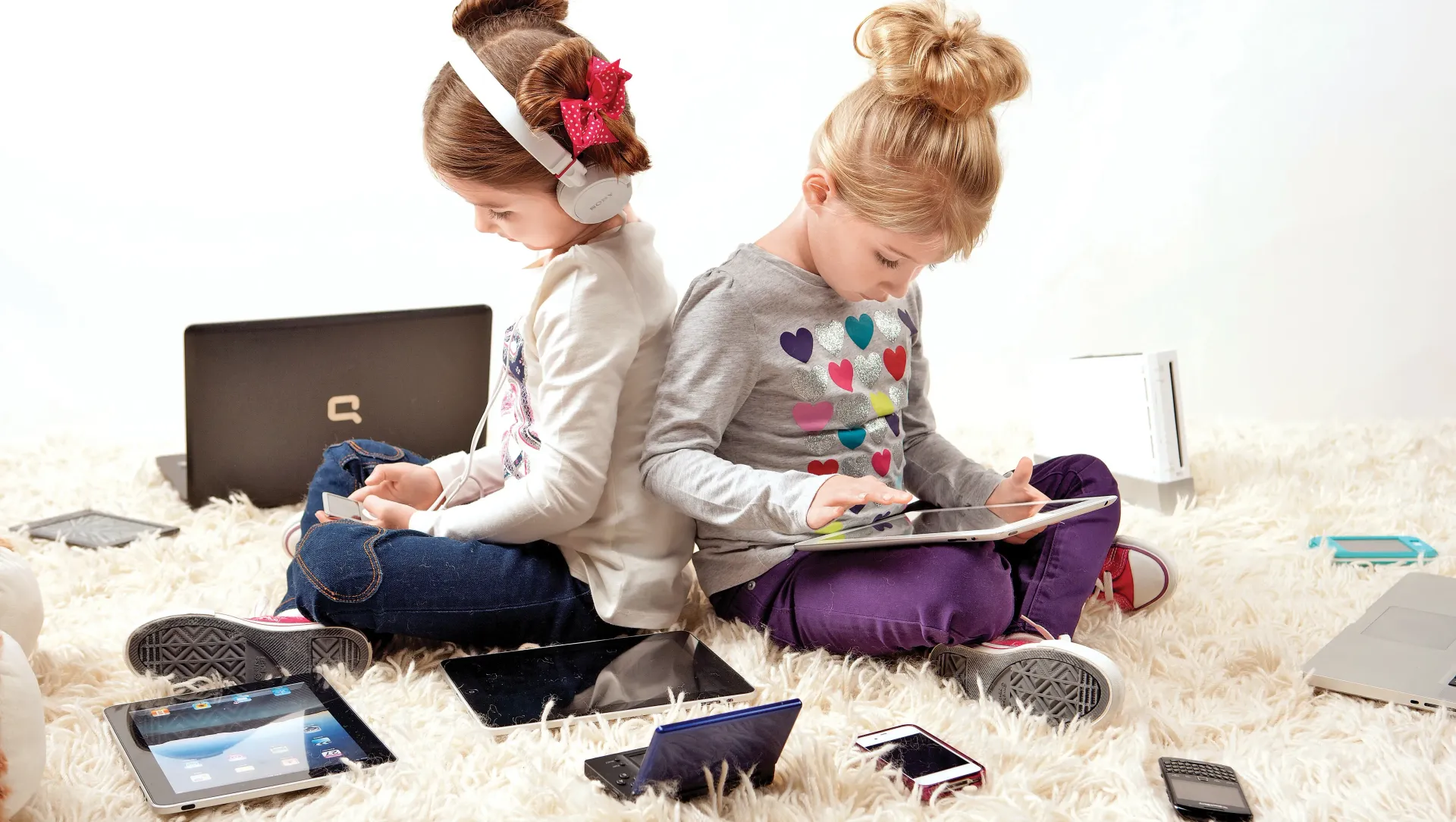 Two children using phones, tablets, and other digital devices