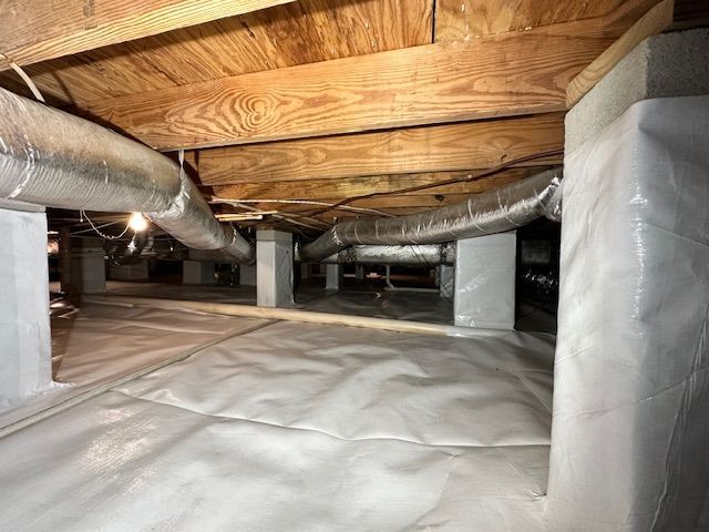 A basement with a lot of ducts and a lot of insulation.