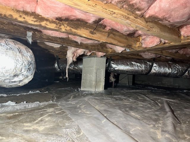 A crawl space with a lot of insulation and a pipe coming out of the ceiling.