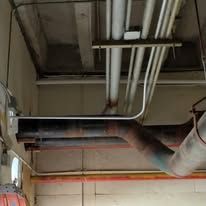 A bunch of pipes are hanging from the ceiling of a building.