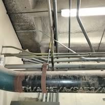 A bunch of pipes are hanging from the ceiling of a building.