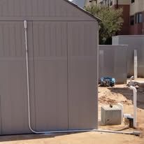 A shed with a pipe attached to the side of it.