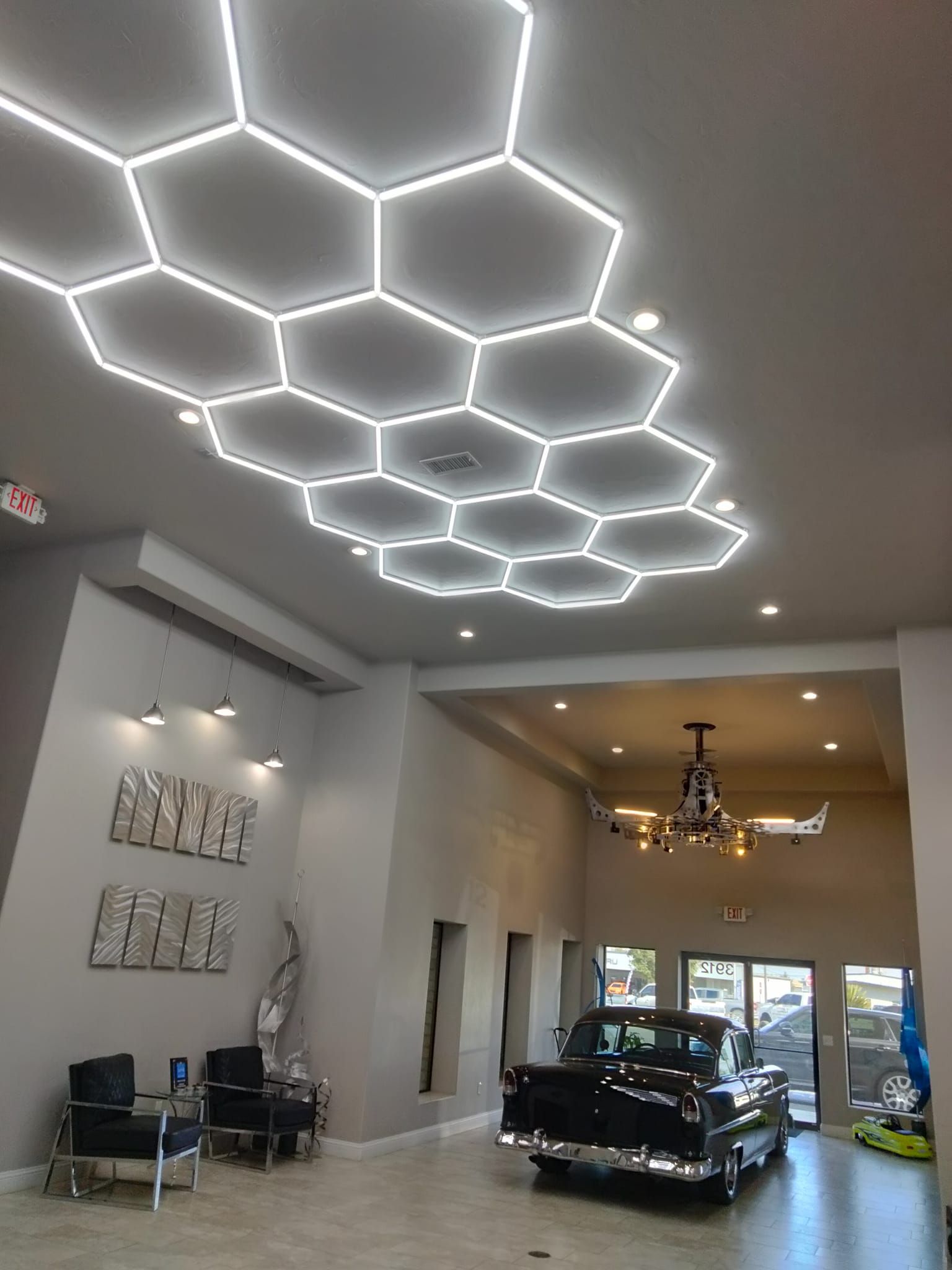 A car is parked in a lobby with a honeycomb ceiling light.