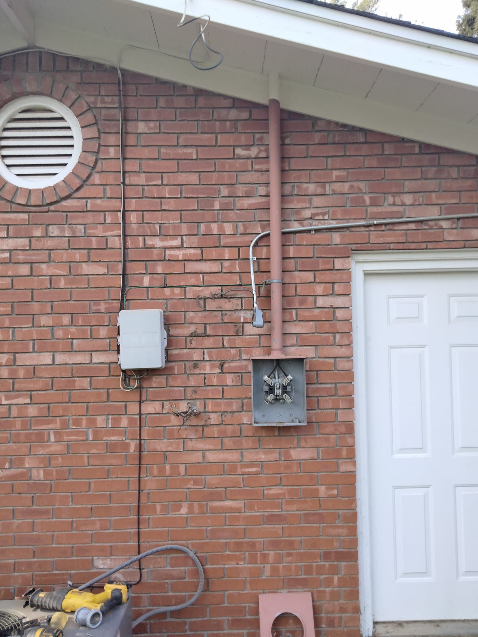 A brick wall with a white door and a white electrical box on it