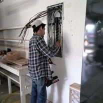 A man is working on an electrical panel on a wall.