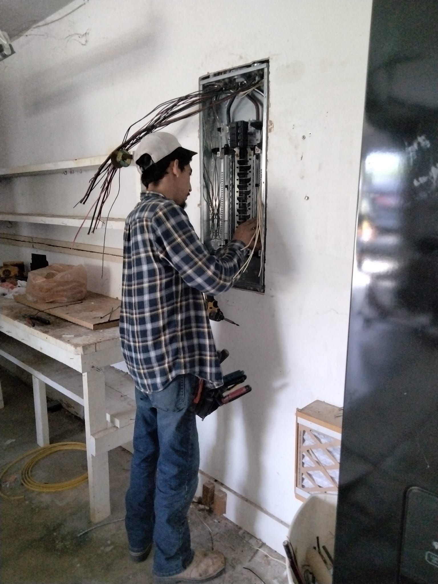A man in a plaid shirt is working on an electrical box