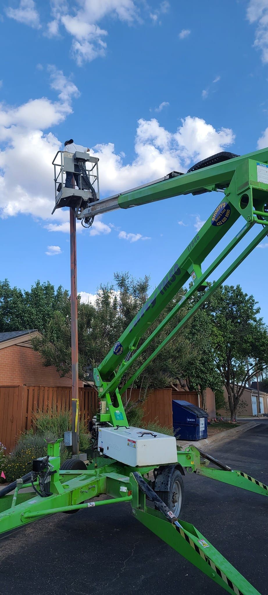 A green crane is sitting on top of a pole.