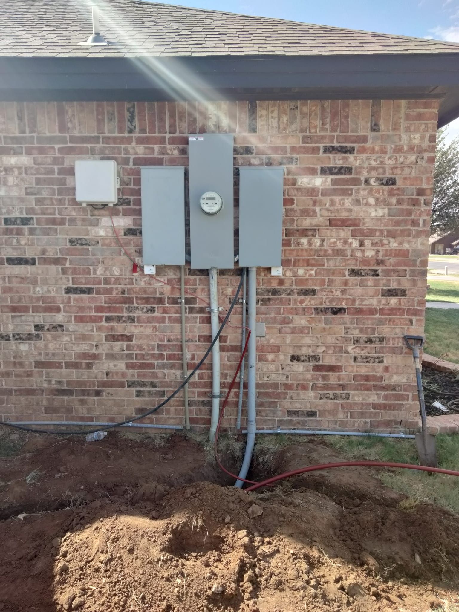 A brick house with a electrical box on the side of it.