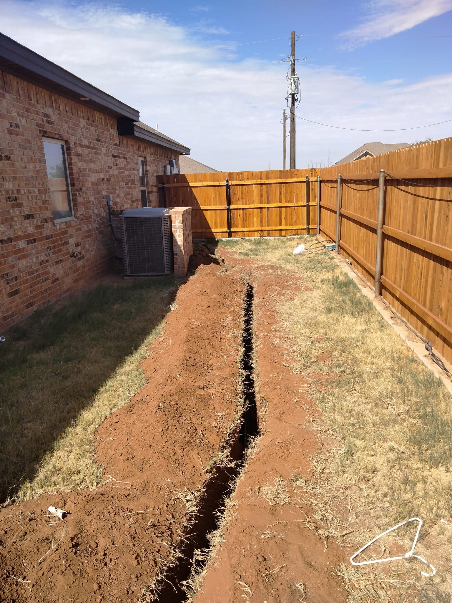 There is a hole in the ground in the backyard of a house.