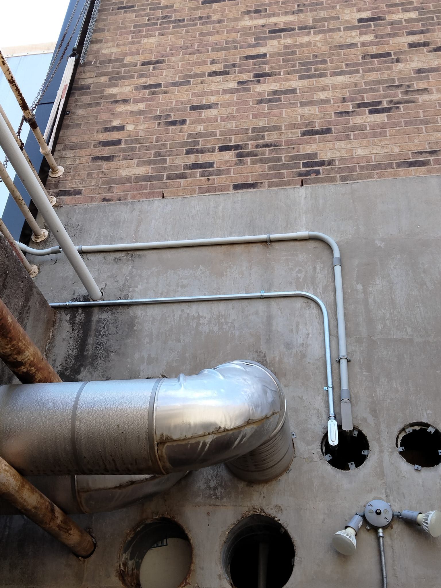 A brick wall with pipes and holes in it