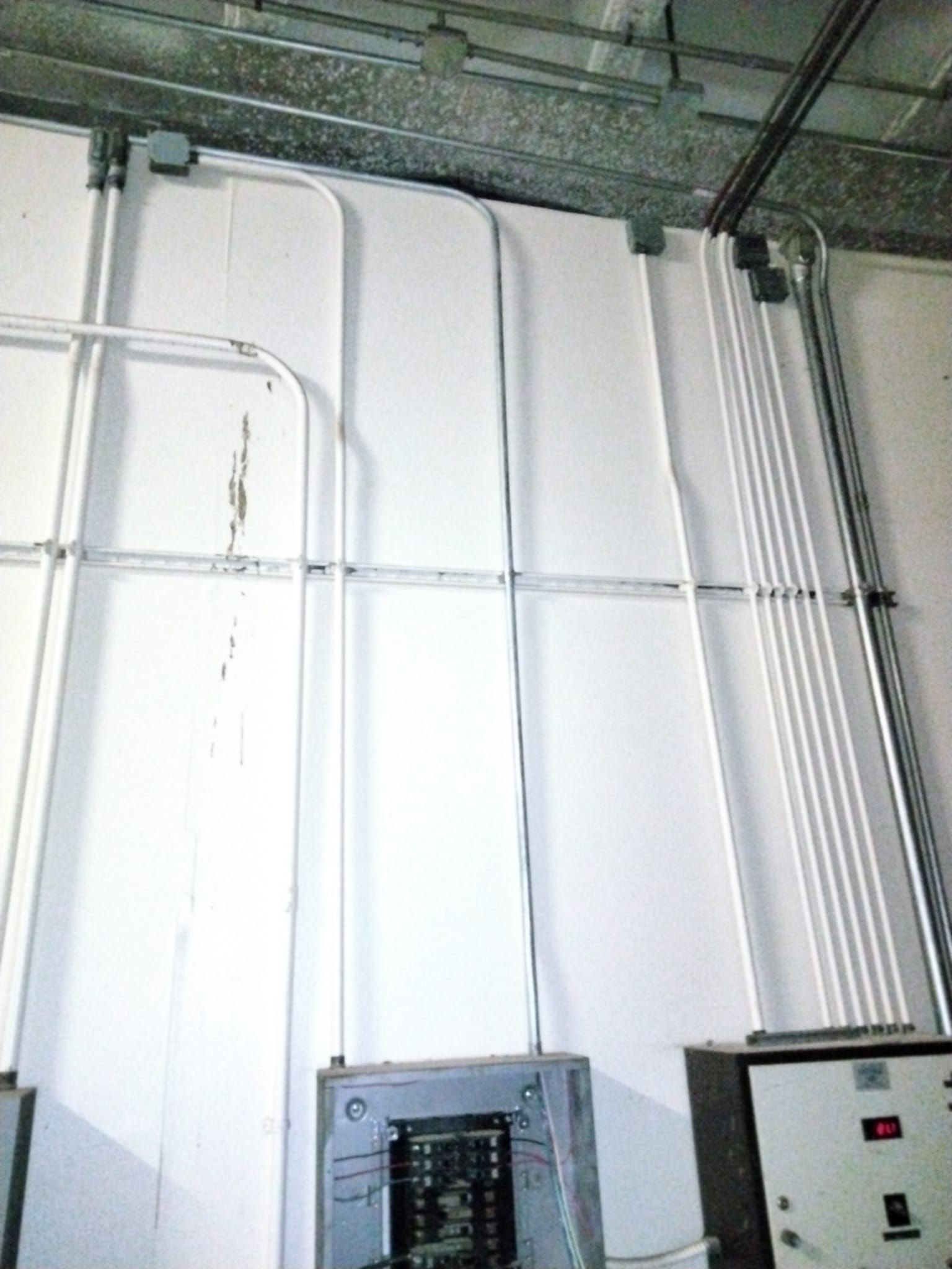 A white wall with electrical wires coming out of it.