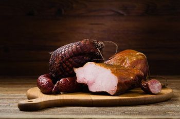 assortment of smoked meats on wooden cutting board