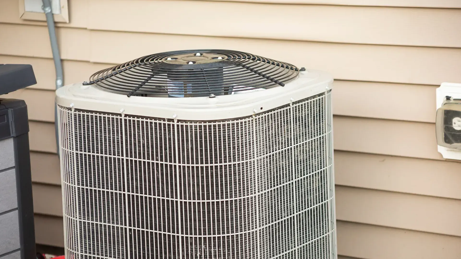 Air conditioner unit against a beige house exterior.
