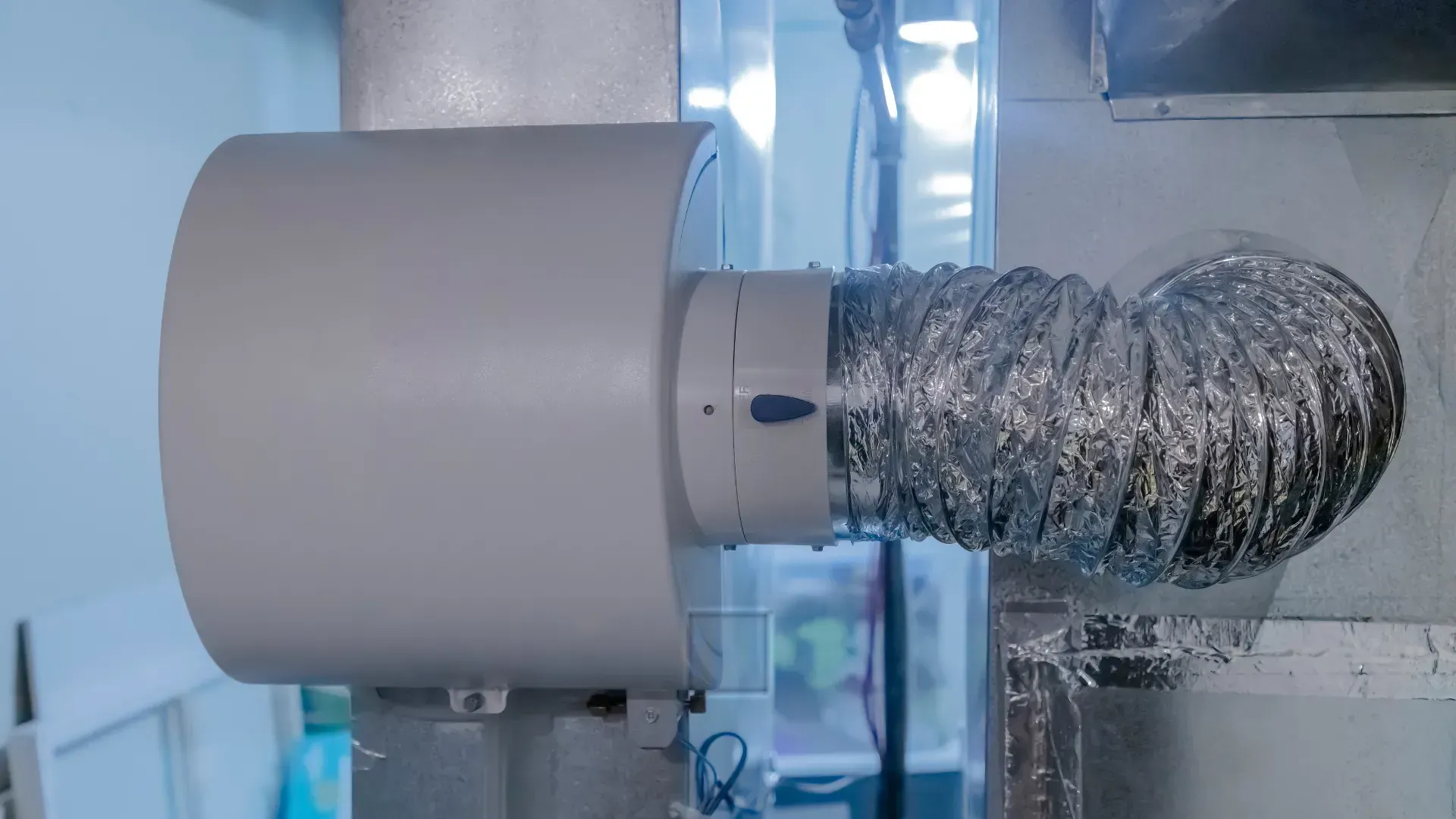 Silver flexible vent attached to a machine, likely for fume extraction, inside a workshop.