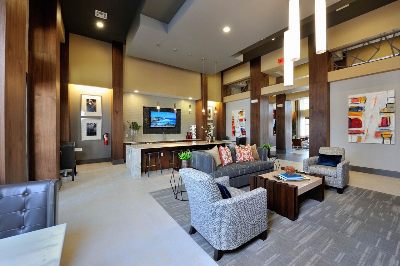 Spacious residential lobby with seating area, stone bar, and contemporary artwork at Olympus Falcon Landing.