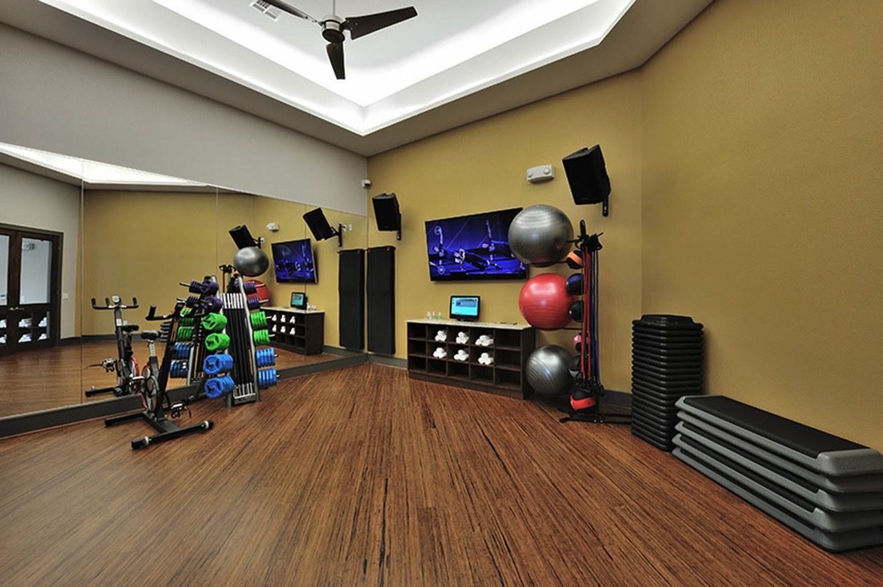Indoor apartment gym with weights, medicine balls, mats, and mirrors at Olympus Falcon Landing.