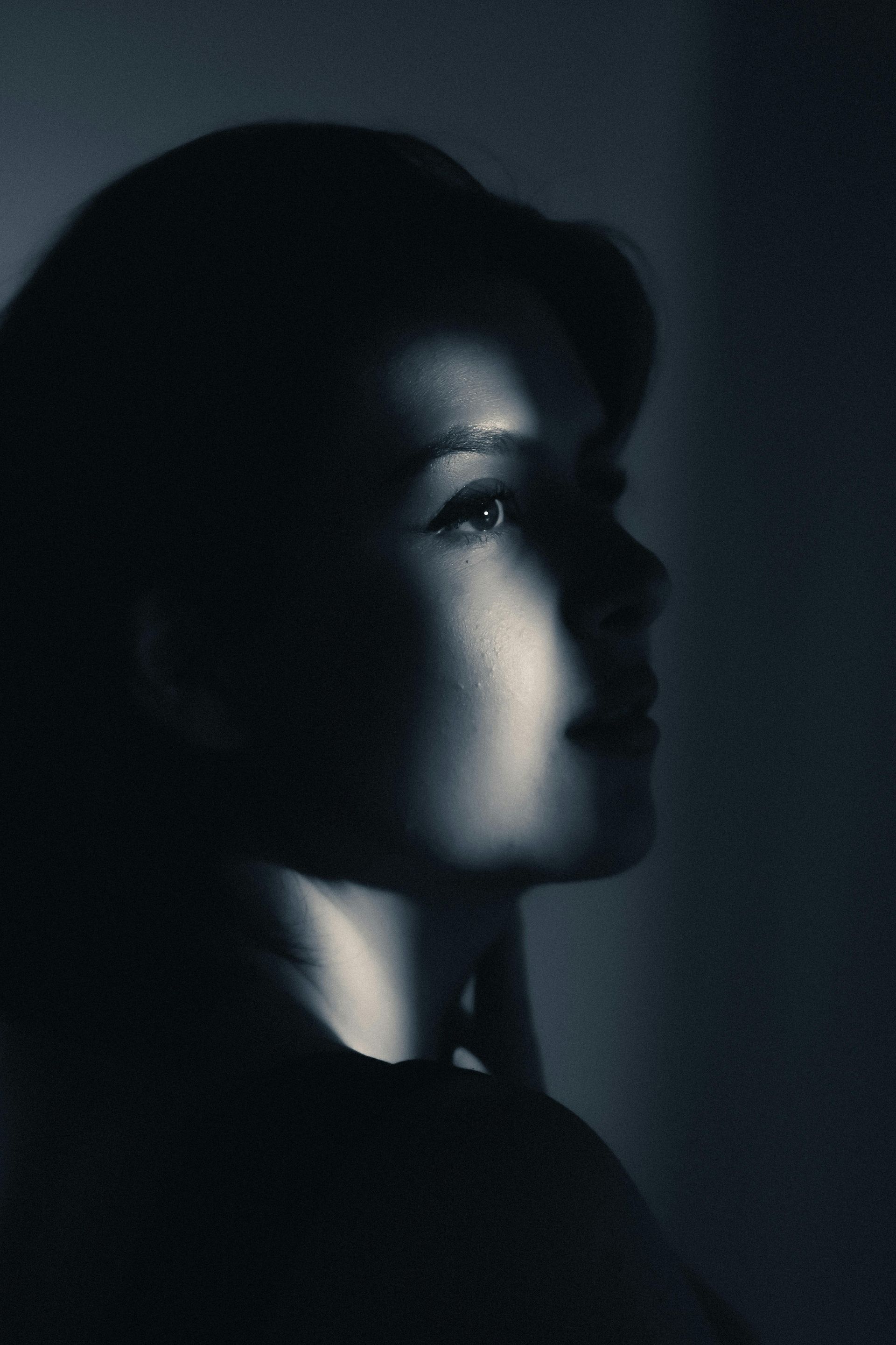 Perfil de una persona en sombra, rostro iluminado desde arriba; expresión contemplativa.