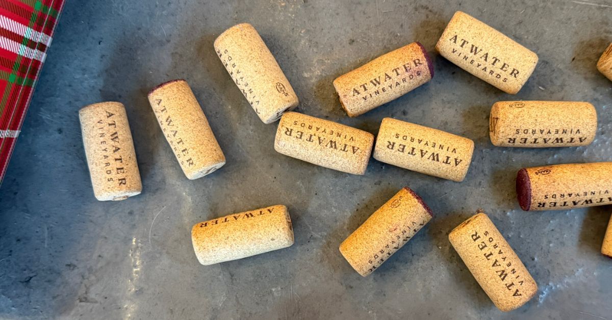 Cork wine stoppers scattered on a grey surface, some with the word 