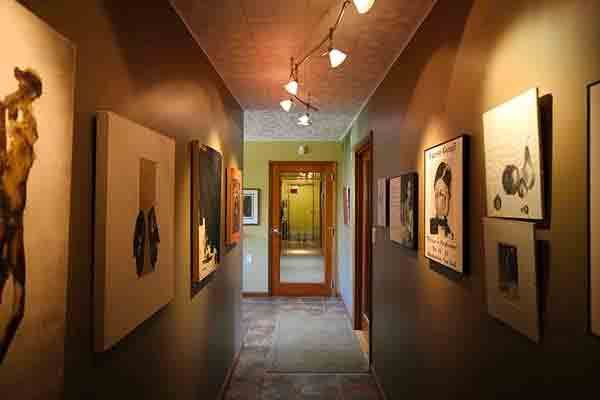 A long hallway with paintings on the walls and a door.