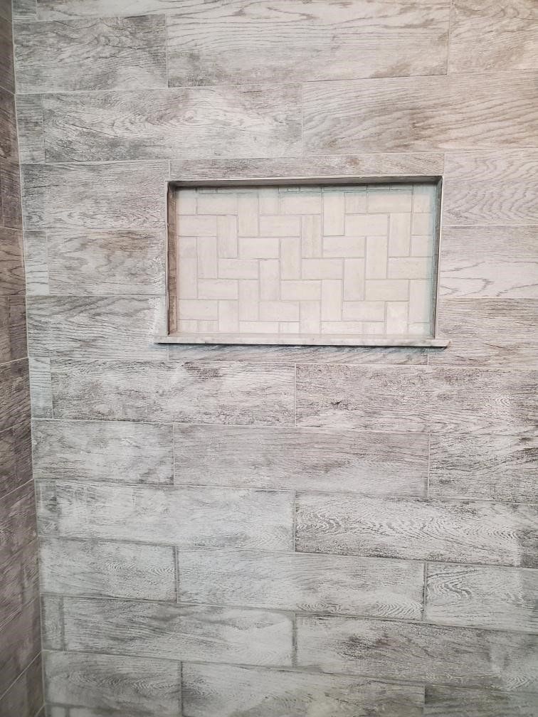 A shower stall with a tiled niche in the wall.