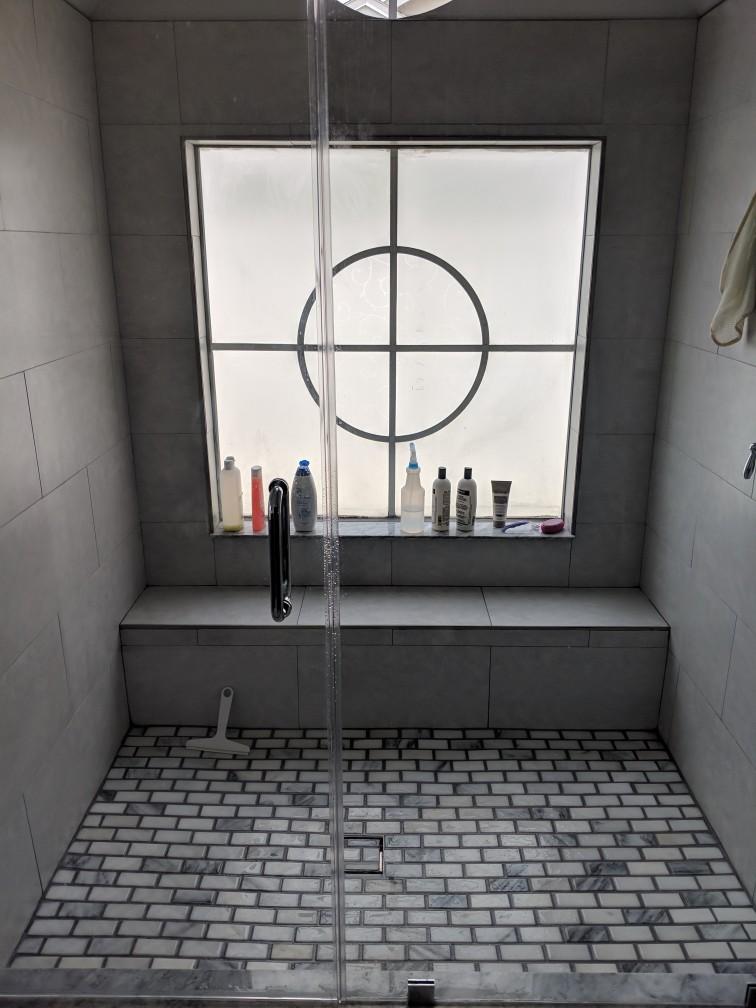A bathroom with a walk in shower and a window.