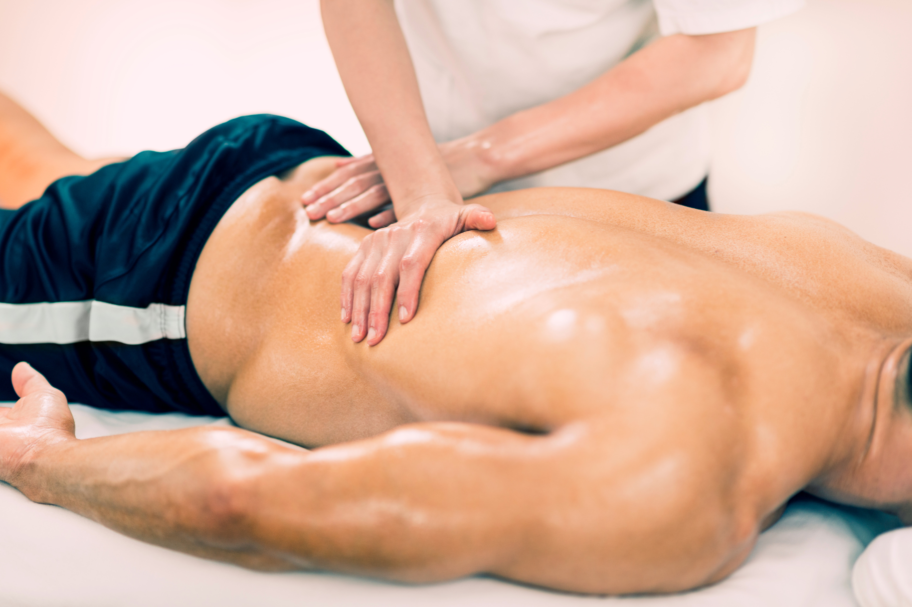 A man is laying on a table getting a massage from a woman.