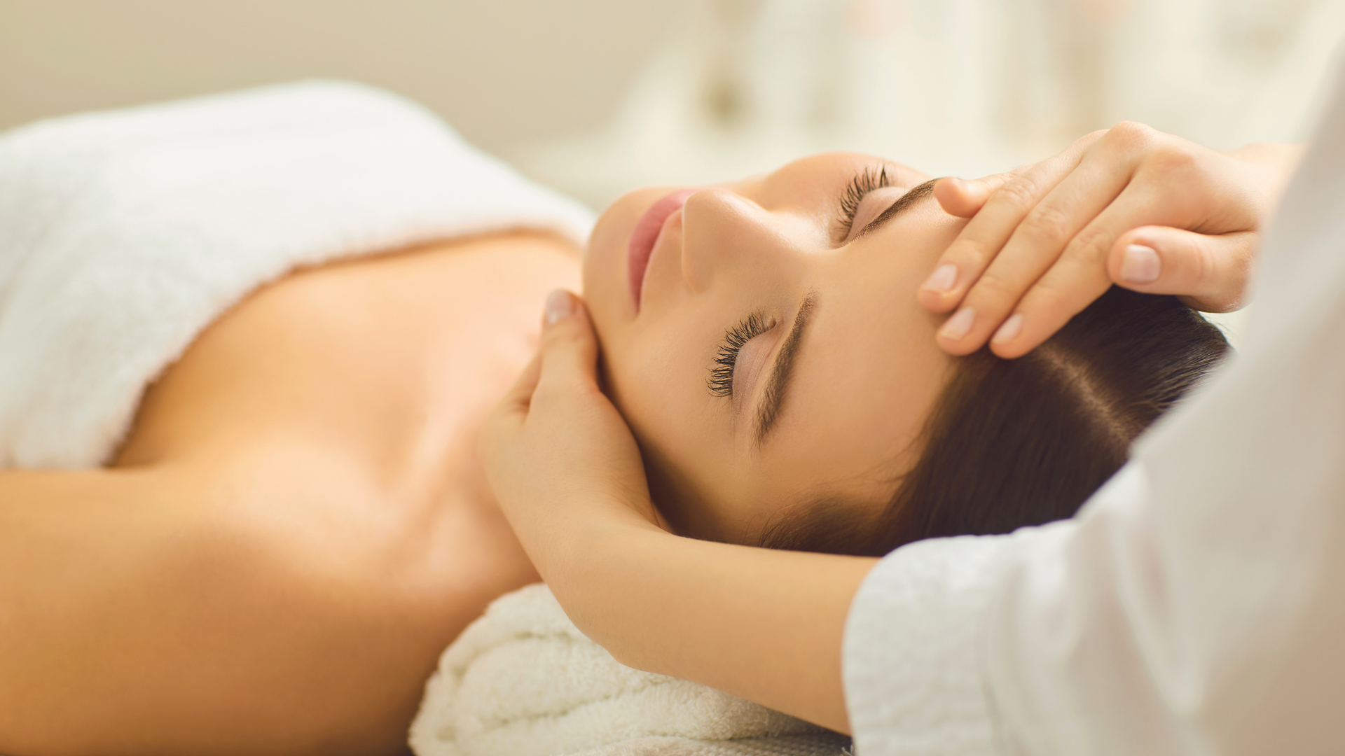 A woman is getting a facial massage at a spa.