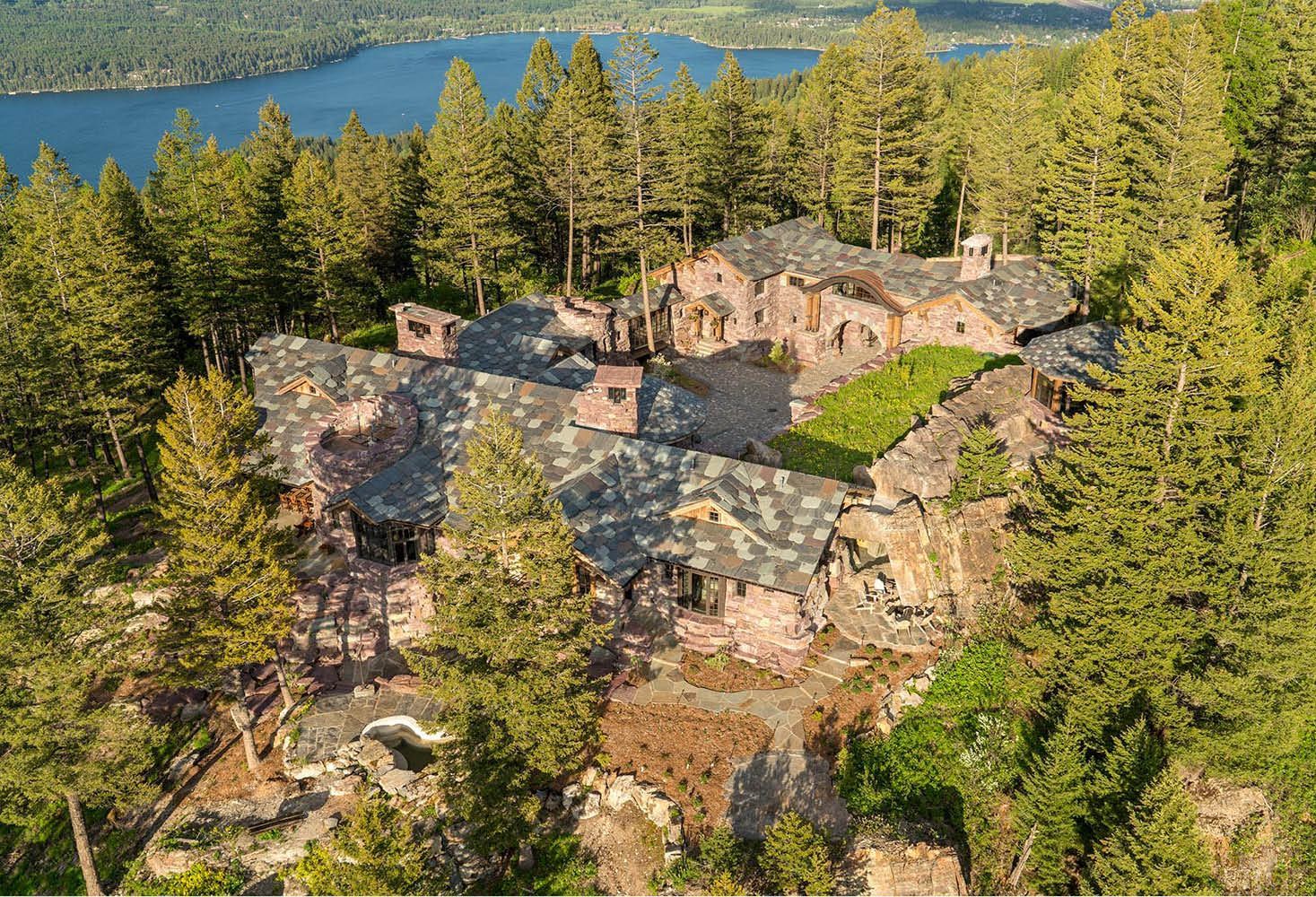 An aerial view of a large house surrounded by trees and a lake.