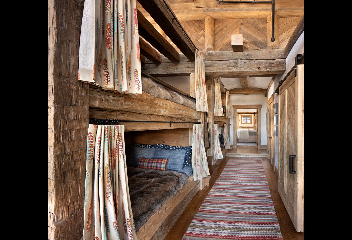 A long hallway with bunk beds and a rug on the floor.