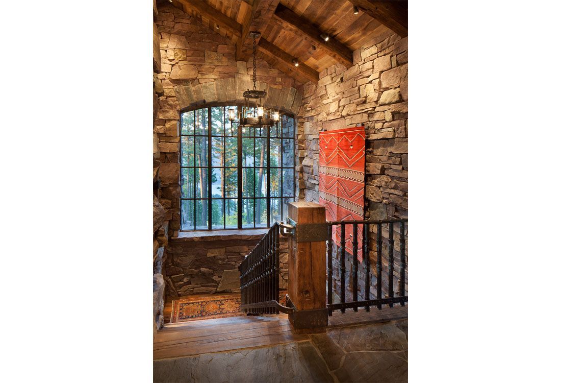 A staircase with a stone wall and a large window.