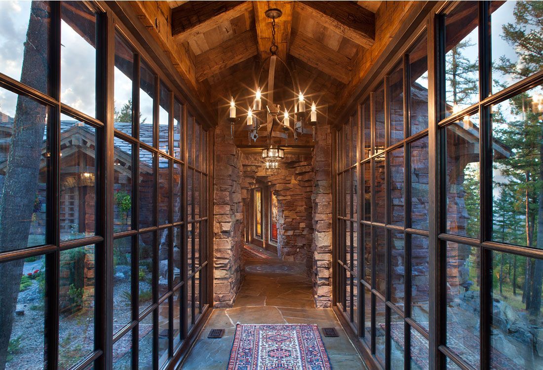 A long hallway with lots of windows and a chandelier hanging from the ceiling.