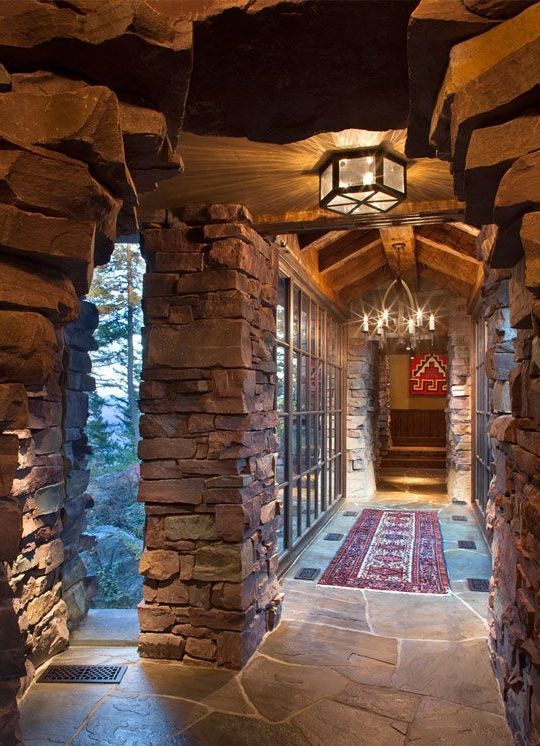 A long stone hallway with a chandelier hanging from the ceiling.