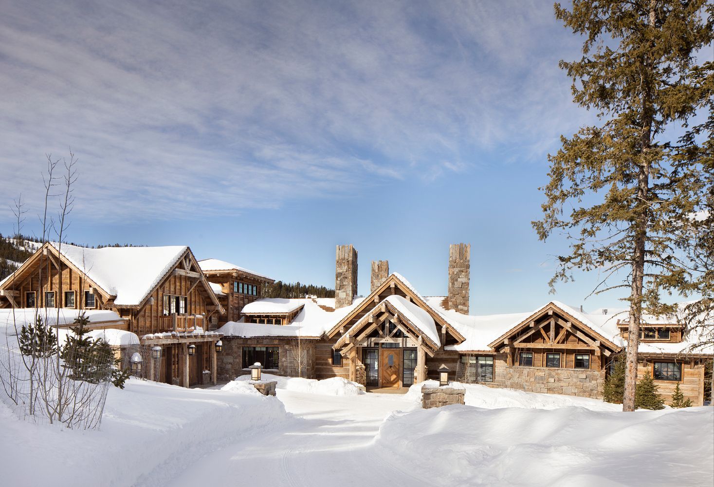 A large house is surrounded by snow and trees