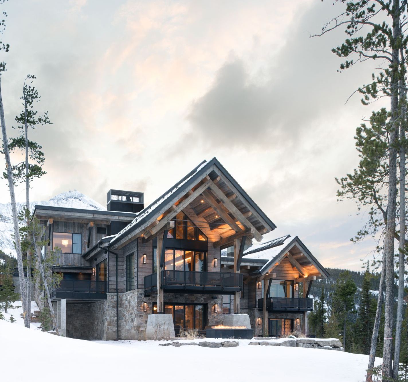 A large wooden house in the middle of a snowy forest.