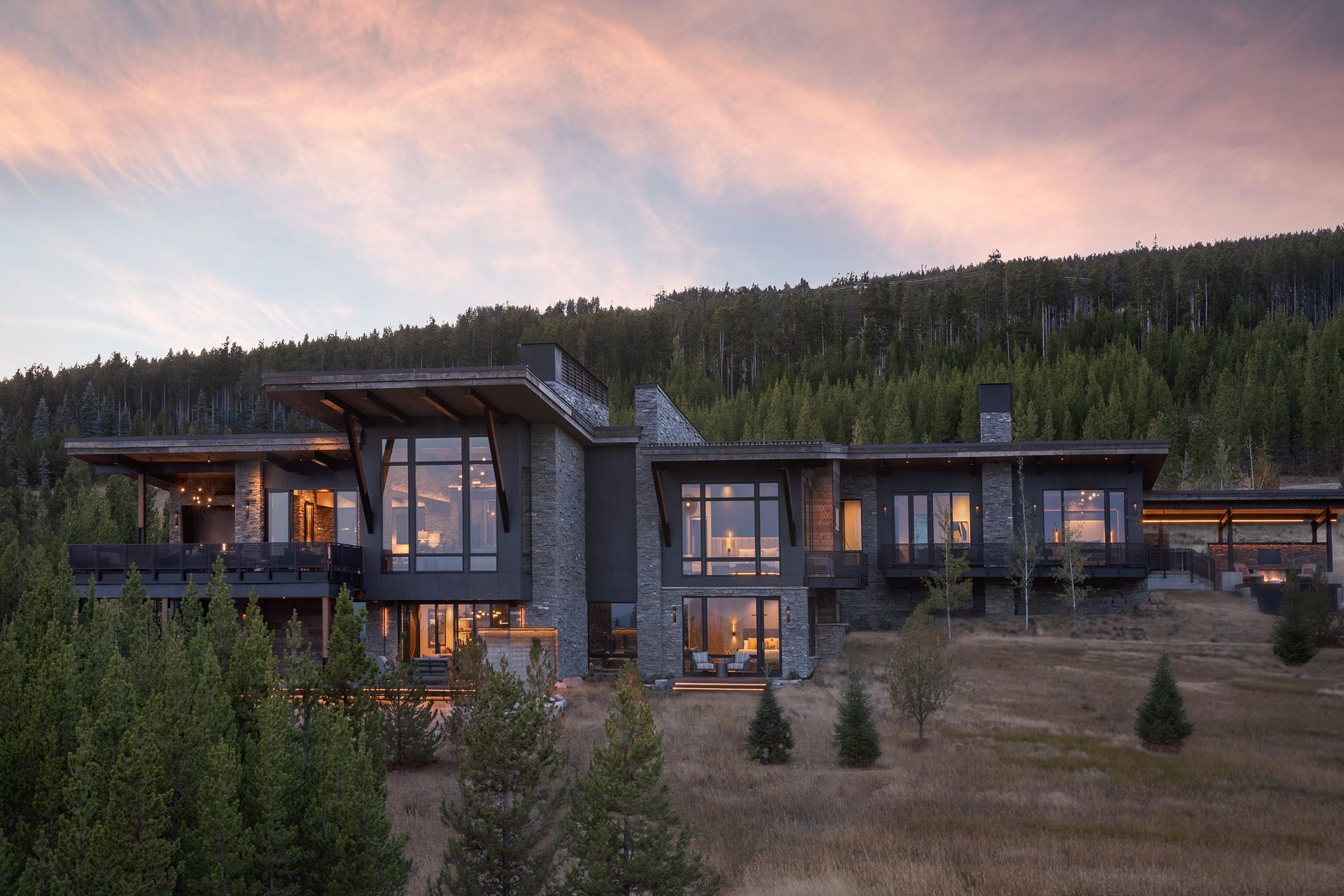 A large house is sitting on top of a hill surrounded by trees.