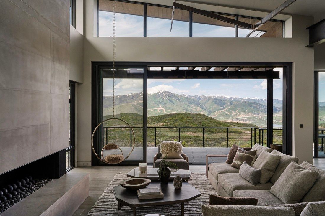 A living room with a couch , chairs and a fireplace with a view of mountains.