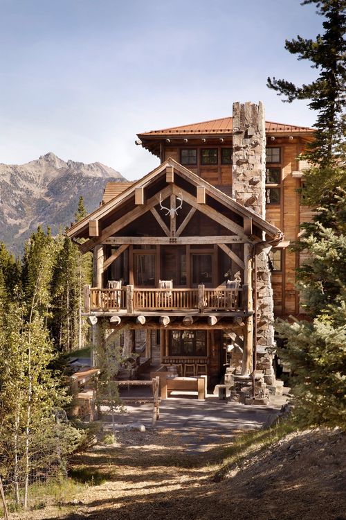 A large wooden house surrounded by trees and mountains