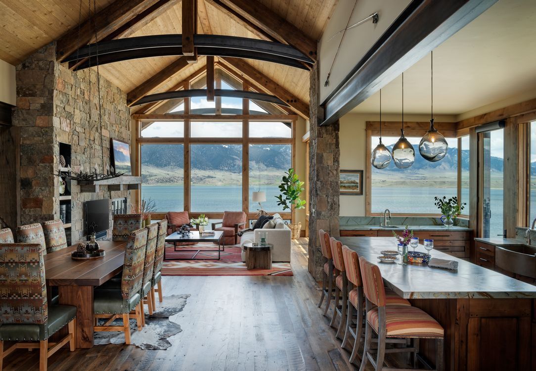 A living room and dining room in a house with a view of a lake.