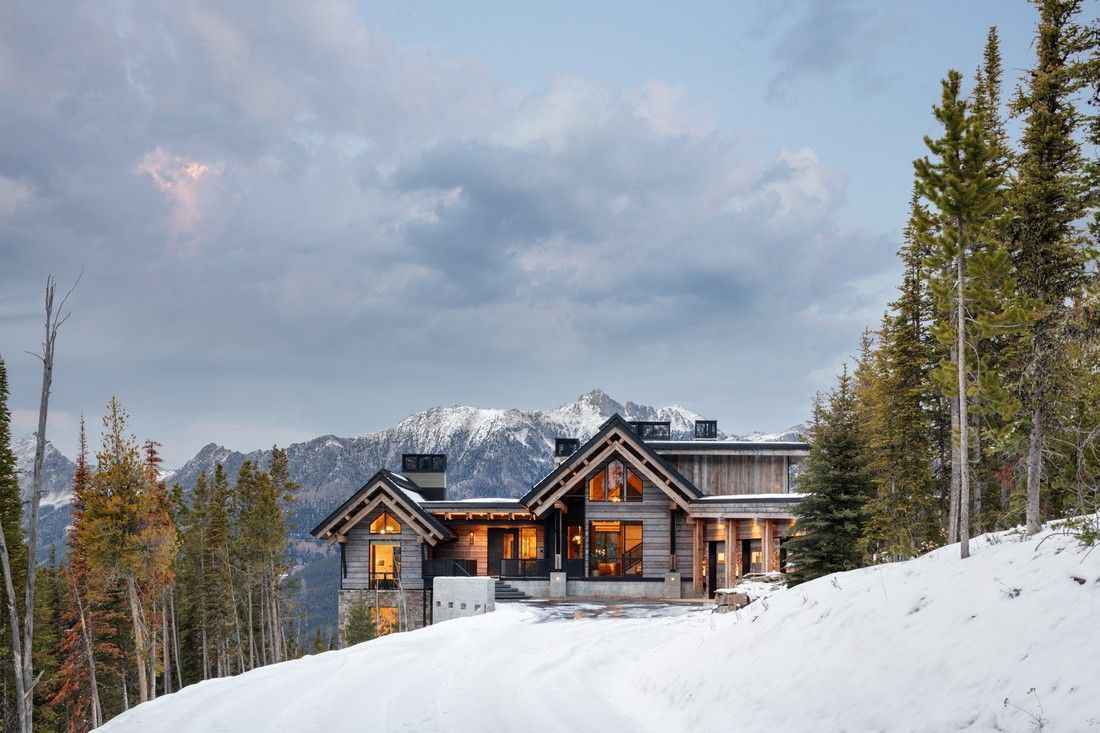 A large wooden house in the middle of a snowy forest.