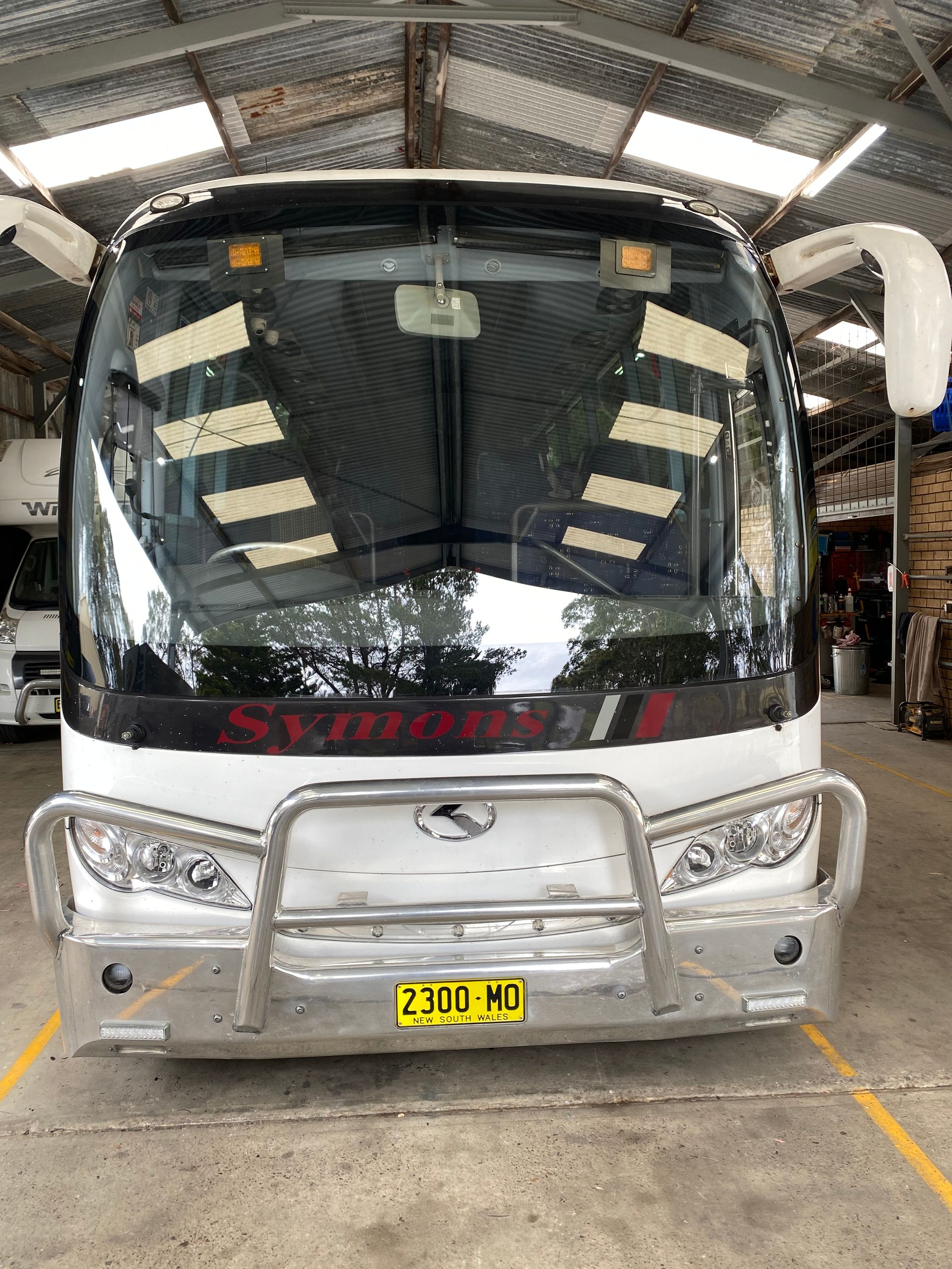 A Man Is Installing A Windshield On A Car In Front Of A House — Eurobodalla Windscreens in Moruya, NSW