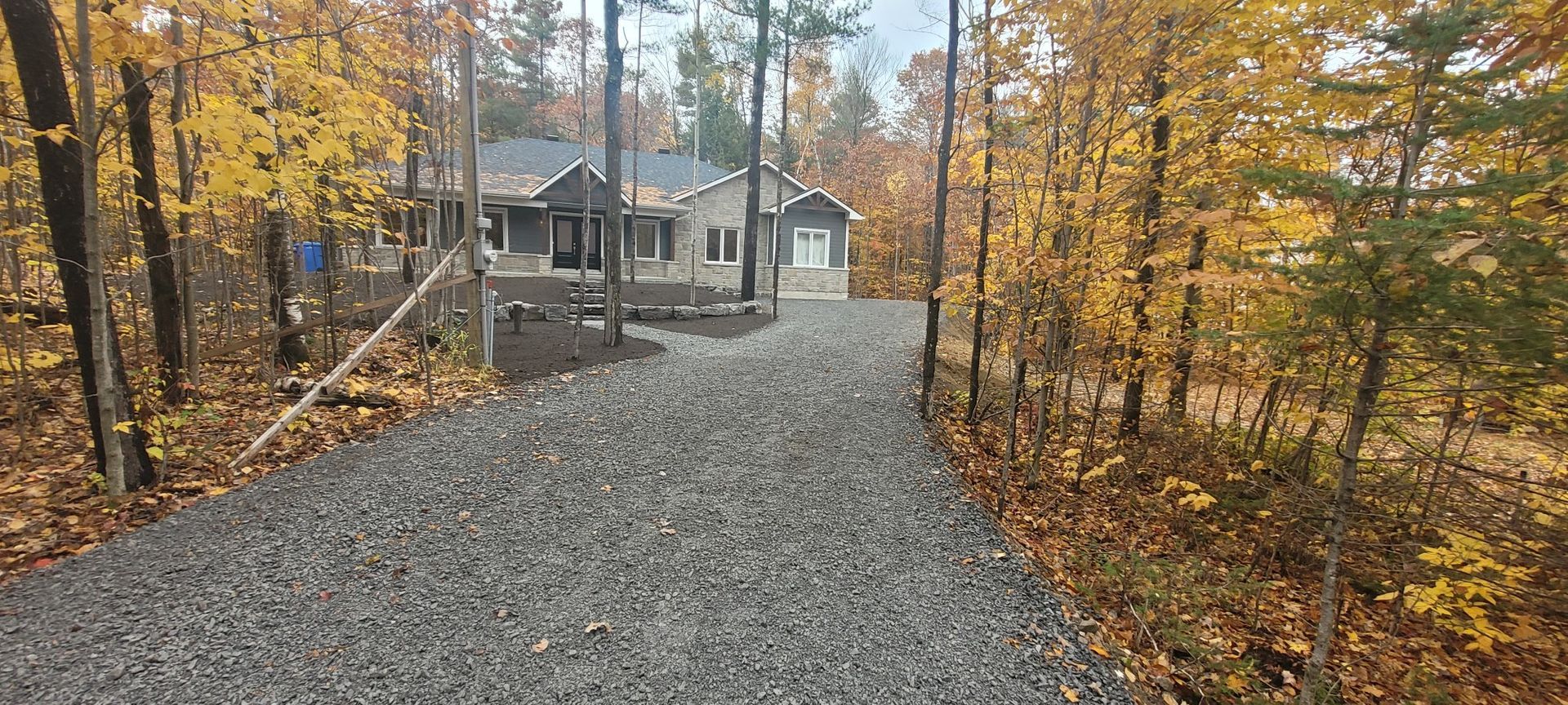 Une allée de gravier menant à une maison dans les bois.